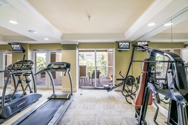 gym featuring a raised ceiling, ornamental molding, light carpet, and a wealth of natural light