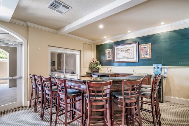 interior space featuring beam ceiling, crown molding, a textured ceiling, and light carpet