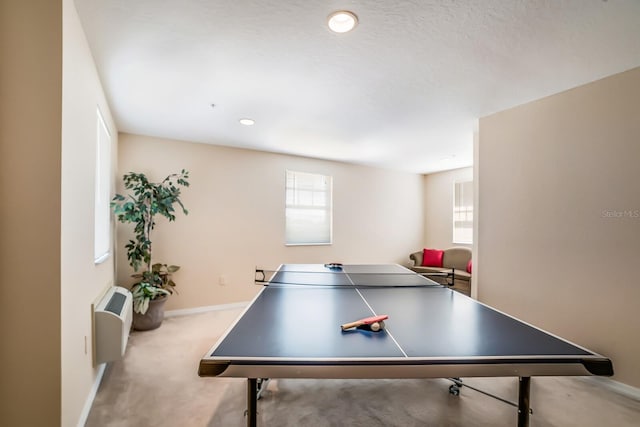 game room with an AC wall unit, light colored carpet, and a textured ceiling