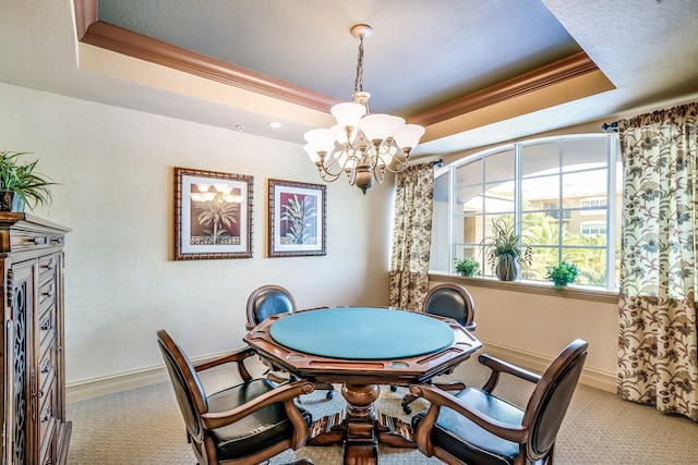 carpeted dining area with ornamental molding, a tray ceiling, and a notable chandelier