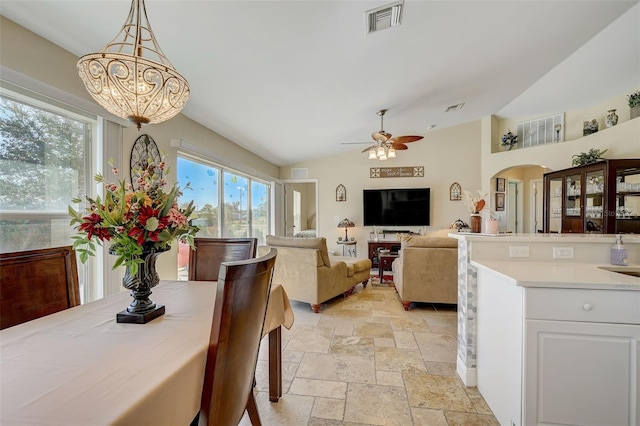 dining area featuring ceiling fan with notable chandelier and lofted ceiling