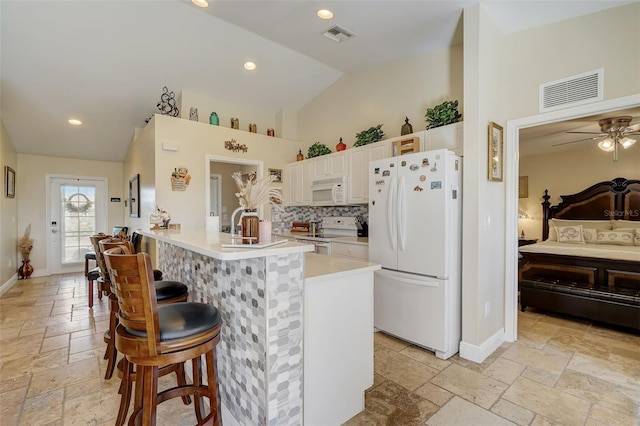 kitchen with a kitchen breakfast bar, white appliances, ceiling fan, white cabinetry, and lofted ceiling