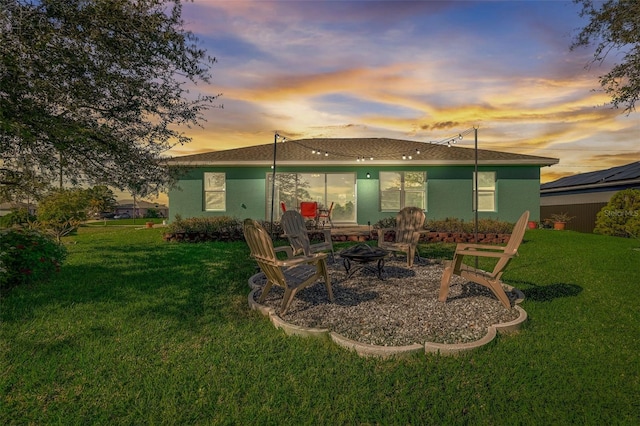 back house at dusk featuring a yard and an outdoor fire pit