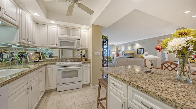 kitchen with light stone counters, white appliances, ceiling fan, white cabinets, and light tile patterned flooring