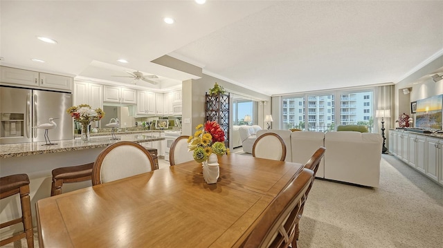 carpeted dining space featuring ceiling fan and crown molding