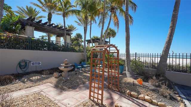 view of patio / terrace featuring a playground, a pergola, a water view, and a beach view