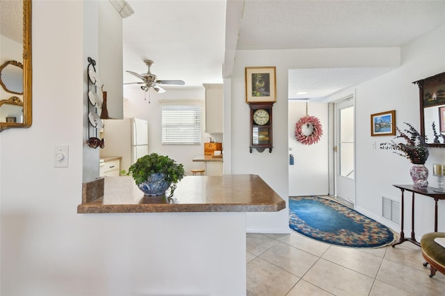 entryway featuring light tile patterned floors, a textured ceiling, and ceiling fan