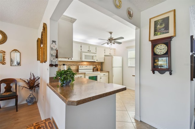 kitchen with kitchen peninsula, ceiling fan, white appliances, and a textured ceiling