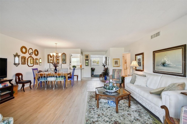 living room featuring light hardwood / wood-style floors, a textured ceiling, and an inviting chandelier