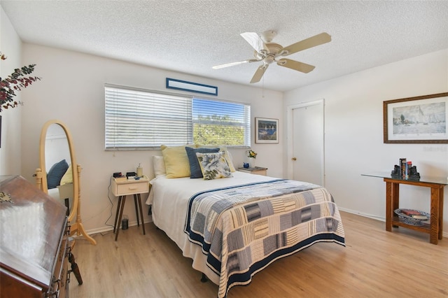 bedroom featuring ceiling fan, light hardwood / wood-style floors, and a textured ceiling