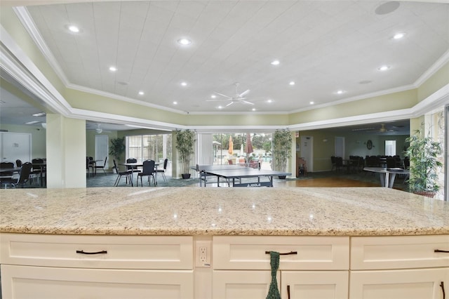 kitchen with ceiling fan, light stone countertops, and ornamental molding