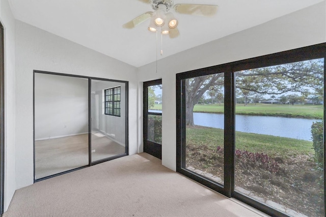 unfurnished sunroom with ceiling fan, a water view, and vaulted ceiling