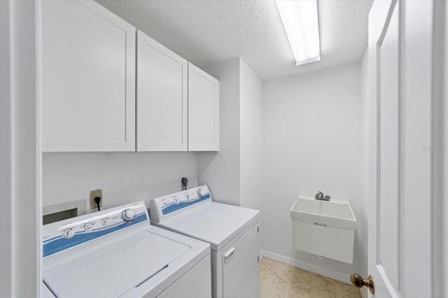 clothes washing area featuring washer and clothes dryer, cabinets, a textured ceiling, and sink