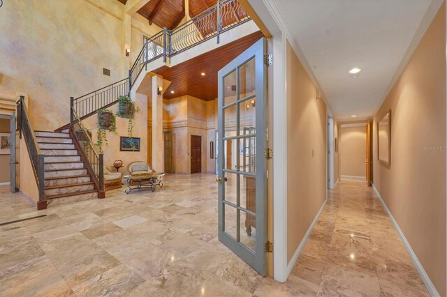 hall with baseboards, marble finish floor, wooden ceiling, and a towering ceiling