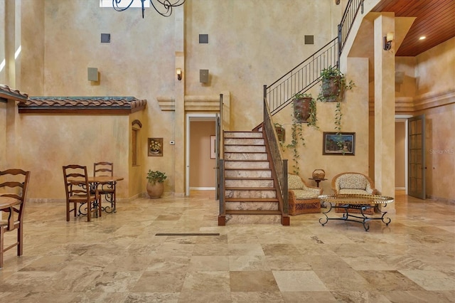 foyer entrance with stairs, a high ceiling, a notable chandelier, and baseboards