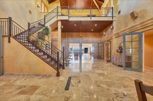 interior space with french doors, baseboards, a towering ceiling, and wooden ceiling