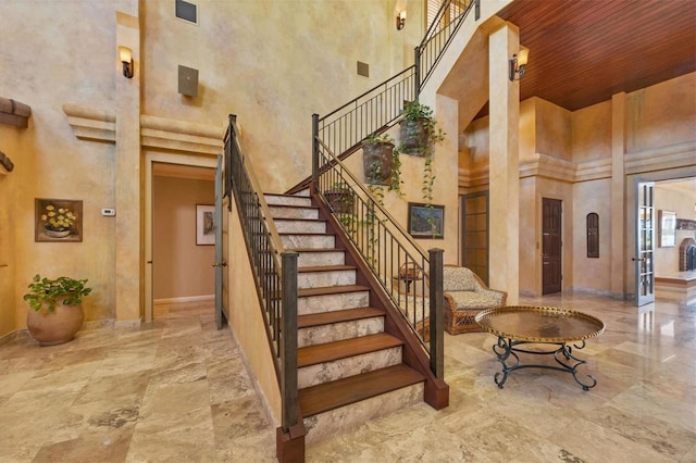 staircase featuring visible vents, baseboards, and a towering ceiling