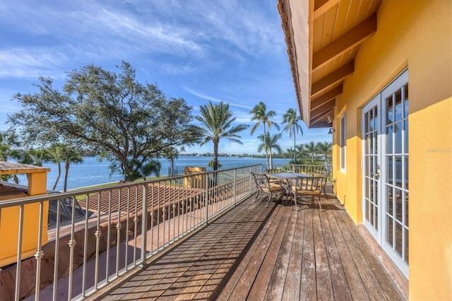 deck with outdoor dining area and a water view