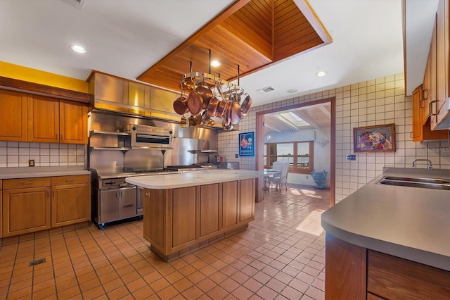 kitchen featuring light countertops, tasteful backsplash, visible vents, and a sink