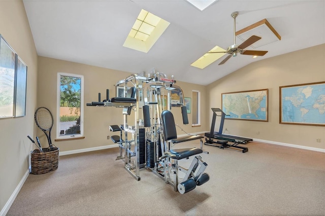 exercise area featuring lofted ceiling with skylight, carpet flooring, baseboards, and ceiling fan