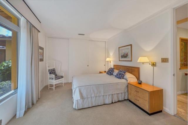 bedroom with light colored carpet, visible vents, and a closet