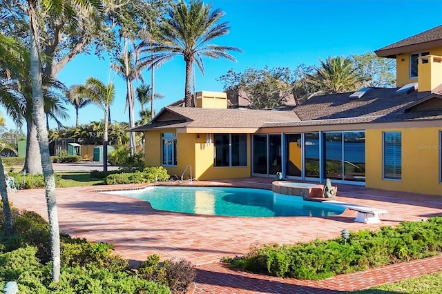 pool featuring a diving board, an in ground hot tub, and a patio area