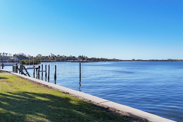 view of dock with a lawn and a water view