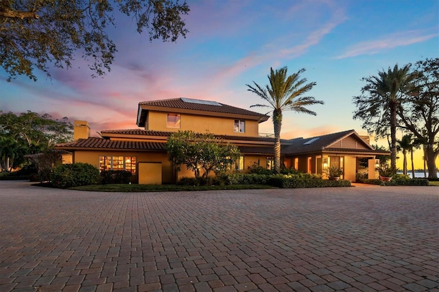 view of front of property featuring a tiled roof, roof mounted solar panels, and stucco siding