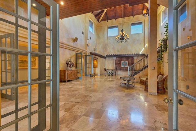 interior space featuring beam ceiling, french doors, an inviting chandelier, wooden ceiling, and stairs