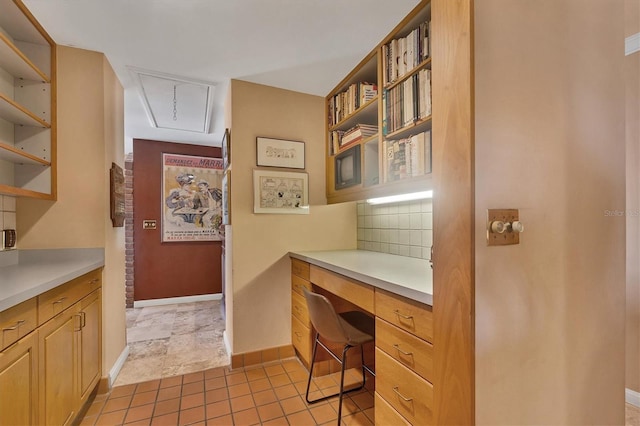 home office with light tile patterned floors, built in desk, attic access, and baseboards