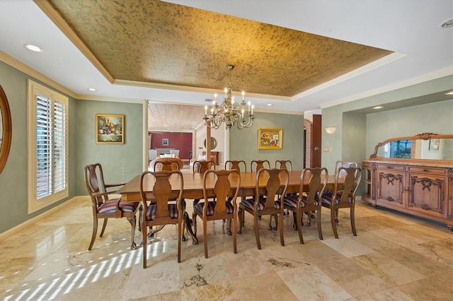 dining space featuring a tray ceiling, baseboards, an inviting chandelier, and crown molding