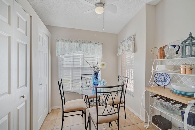 tiled dining room with ceiling fan and a textured ceiling