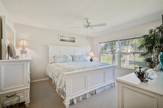 carpeted bedroom featuring ceiling fan and a textured ceiling