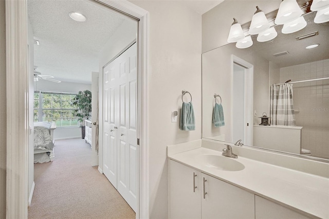 bathroom featuring ceiling fan, vanity, a textured ceiling, and walk in shower