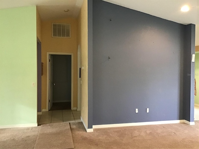 carpeted spare room featuring high vaulted ceiling