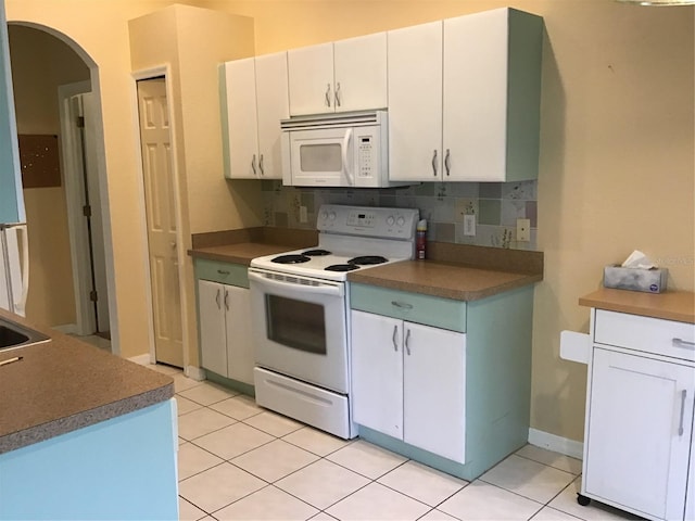 kitchen with white cabinetry, light tile patterned floors, white appliances, and tasteful backsplash