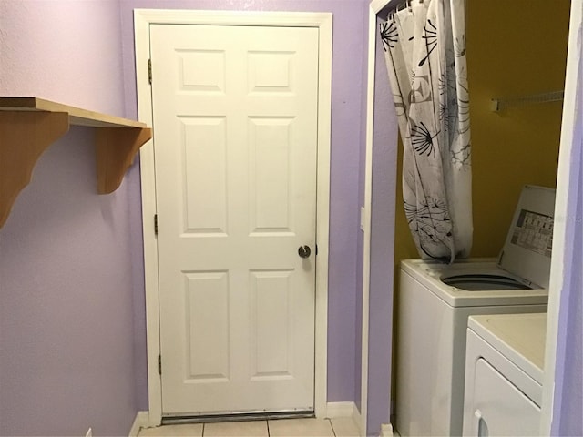 clothes washing area featuring light tile patterned flooring and washer and dryer