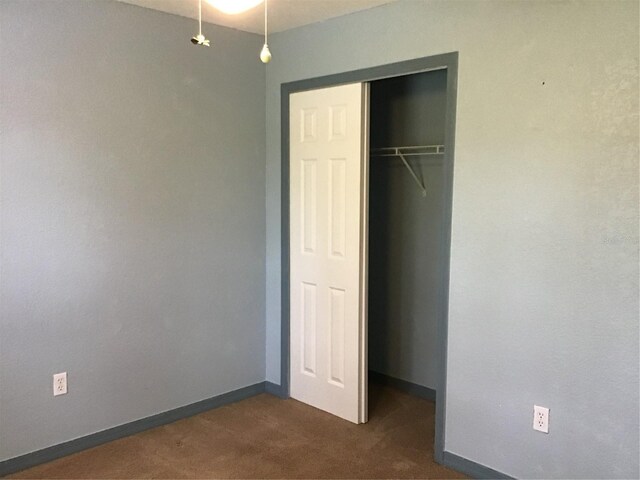 unfurnished bedroom featuring a closet and dark colored carpet