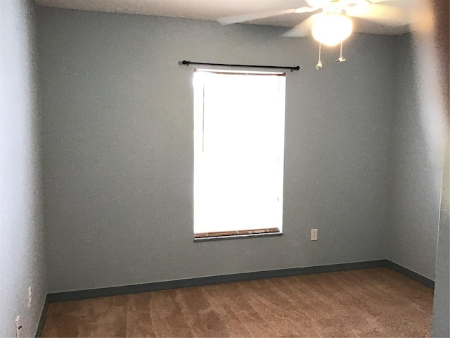 spare room with dark colored carpet and ceiling fan