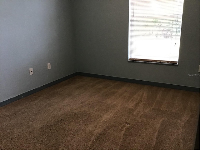 spare room with dark carpet