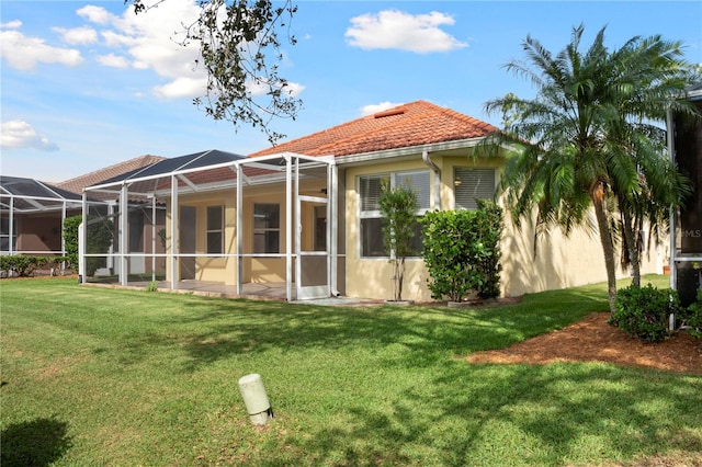 back of house with glass enclosure and a yard