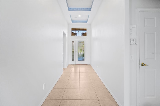 hallway featuring light tile patterned floors and a raised ceiling