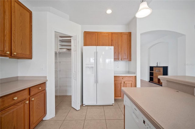 kitchen with light tile patterned flooring, hanging light fixtures, and white appliances