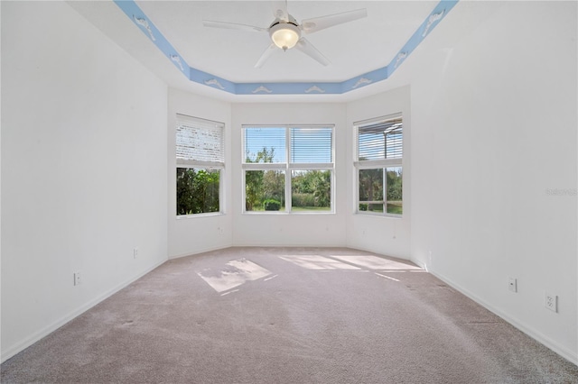 carpeted spare room featuring ceiling fan and a tray ceiling