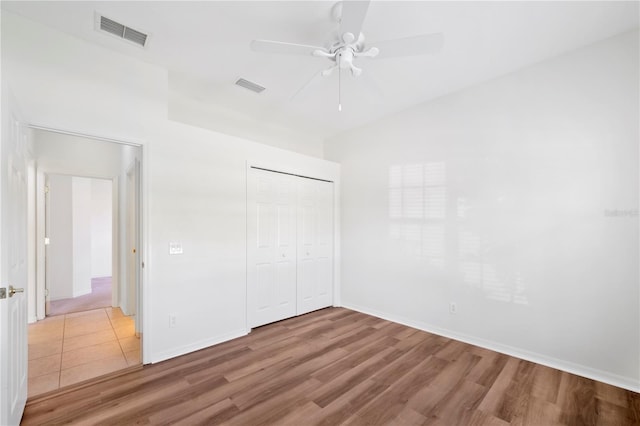 unfurnished bedroom featuring ceiling fan, a closet, and wood-type flooring