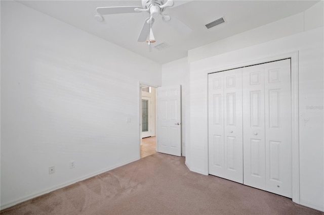 unfurnished bedroom featuring ceiling fan, light colored carpet, and a closet