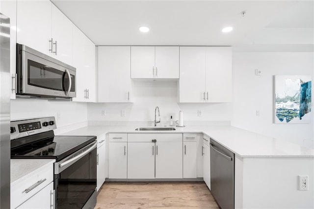 kitchen with sink, light stone counters, white cabinets, appliances with stainless steel finishes, and light hardwood / wood-style flooring