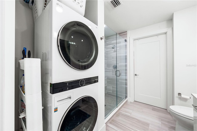 laundry area with light tile flooring and stacked washer and dryer