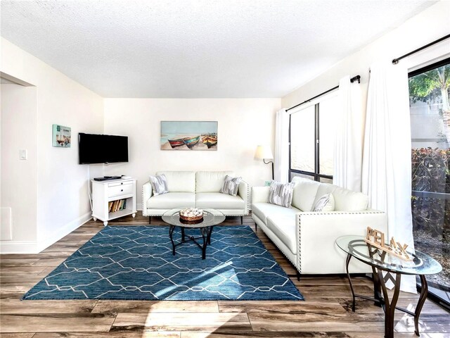 living area with a textured ceiling, wood finished floors, and baseboards