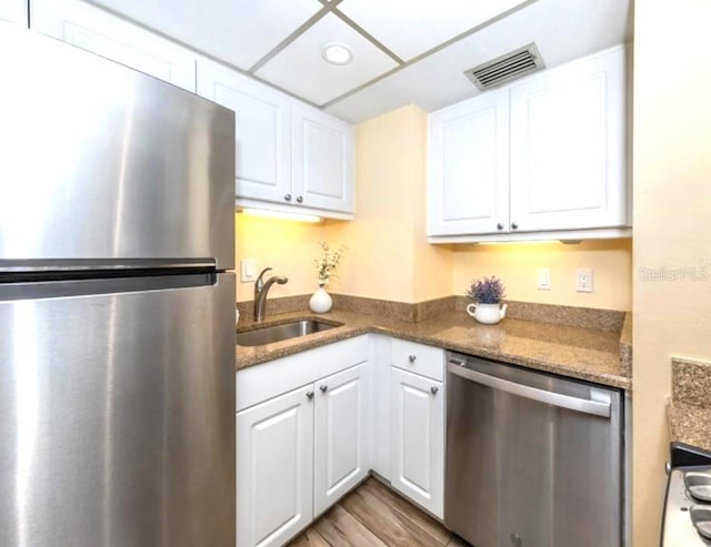 kitchen with white cabinets, visible vents, appliances with stainless steel finishes, wood finished floors, and a sink